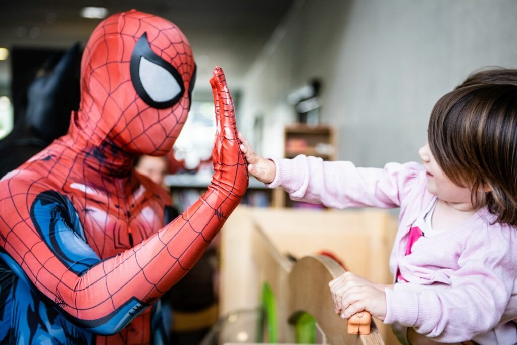 Der Superheld Spiderman gibt einem Kind ein "High Five"